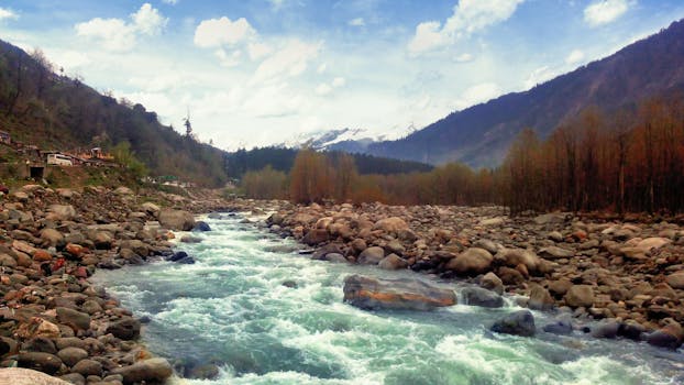 Beautiful mountain river flowing through a rocky valley with distant snowy peaks.