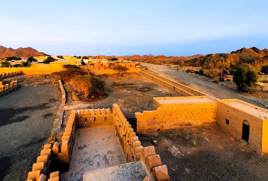Awhala Fort in Fujairah: History, Timings and How to Visit 4 Awhala Fort in Fujairah seen from the top of the watchtower at sunset, with the valley and mountains behind