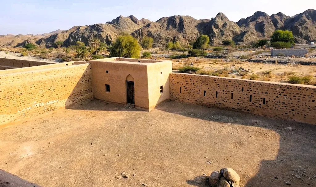Awhala Fort in Fujairah: History, Timings and How to Visit 3 View from the roof of Awhala Fort in Fujairah over the courtyard walls, date farms and Hajar Mountains