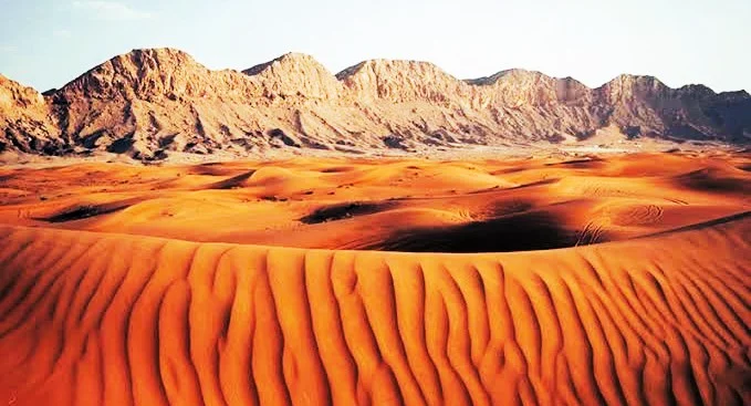 Mleiha Desert in Sharjah: Dunes, Stargazing, Camping and Where to Stay 3 Mleiha desert red dunes in front of rocky mountains in Sharjah