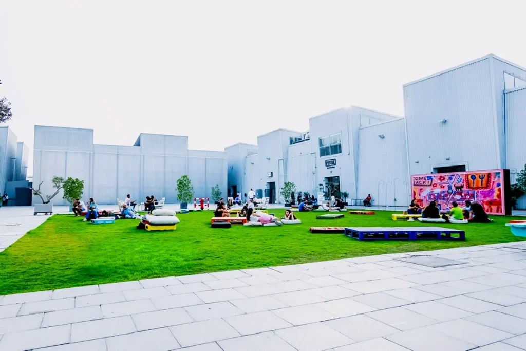 Alserkal Avenue 17th Street Dubai: Best Galleries, Hours and Easy Visitor Tips 4 Visitors relaxing on the lawn at The Yard during an event at Alserkal Avenue Dubai