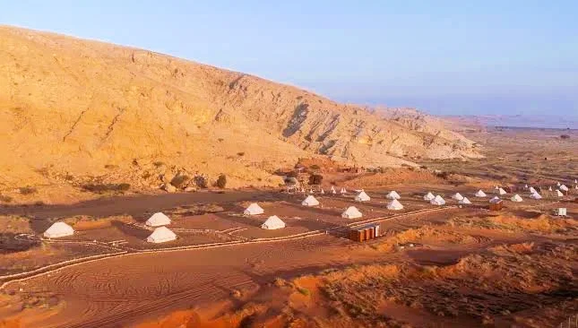 Mleiha Glamping in Sharjah: Tents, Season, Activities and Tips 2 Mleiha glamping site with white bell tents below Al Faya Mountain in Sharjah